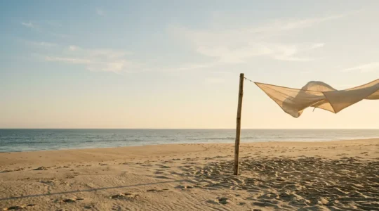 Installation d'un camp de base à la plage avec différentes solutions d'ombrage pour une journée en famille