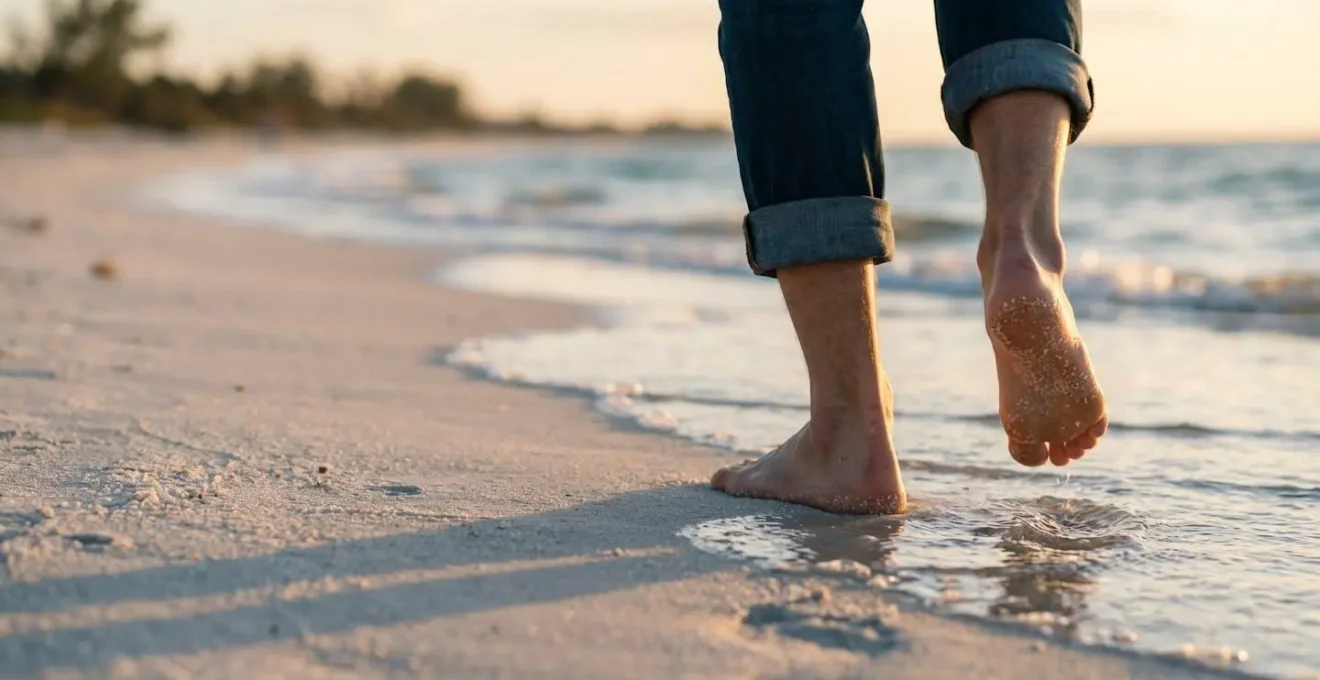 Pieds nus marchant sur du sable fin blanc au bord de l'eau avec des vagues douces