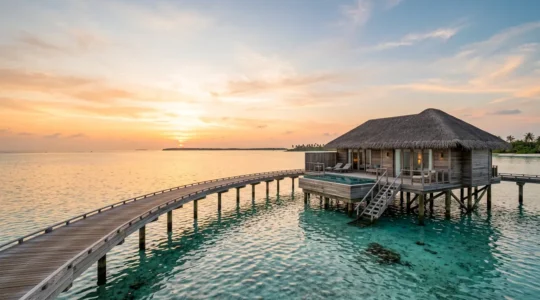 Villa sur pilotis au-dessus d'un lagon tropical turquoise au coucher du soleil