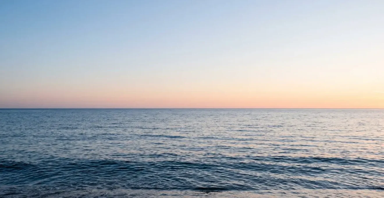 Horizon marin minimaliste avec dégradé de bleus du ciel à l'océan, ligne d'horizon nette et apaisante