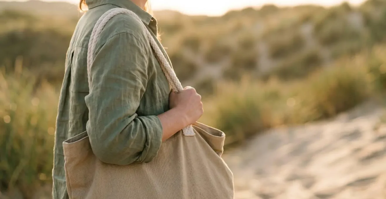 Vue de côté d'une personne portant un sac de plage compact en bandoulière sur fond de dune de sable