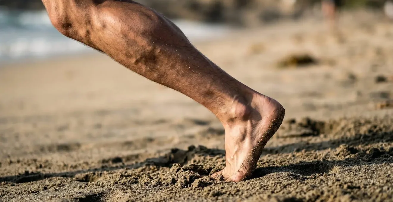 Gros plan sur les muscles des mollets et pieds en action lors d'une marche sur sable instable