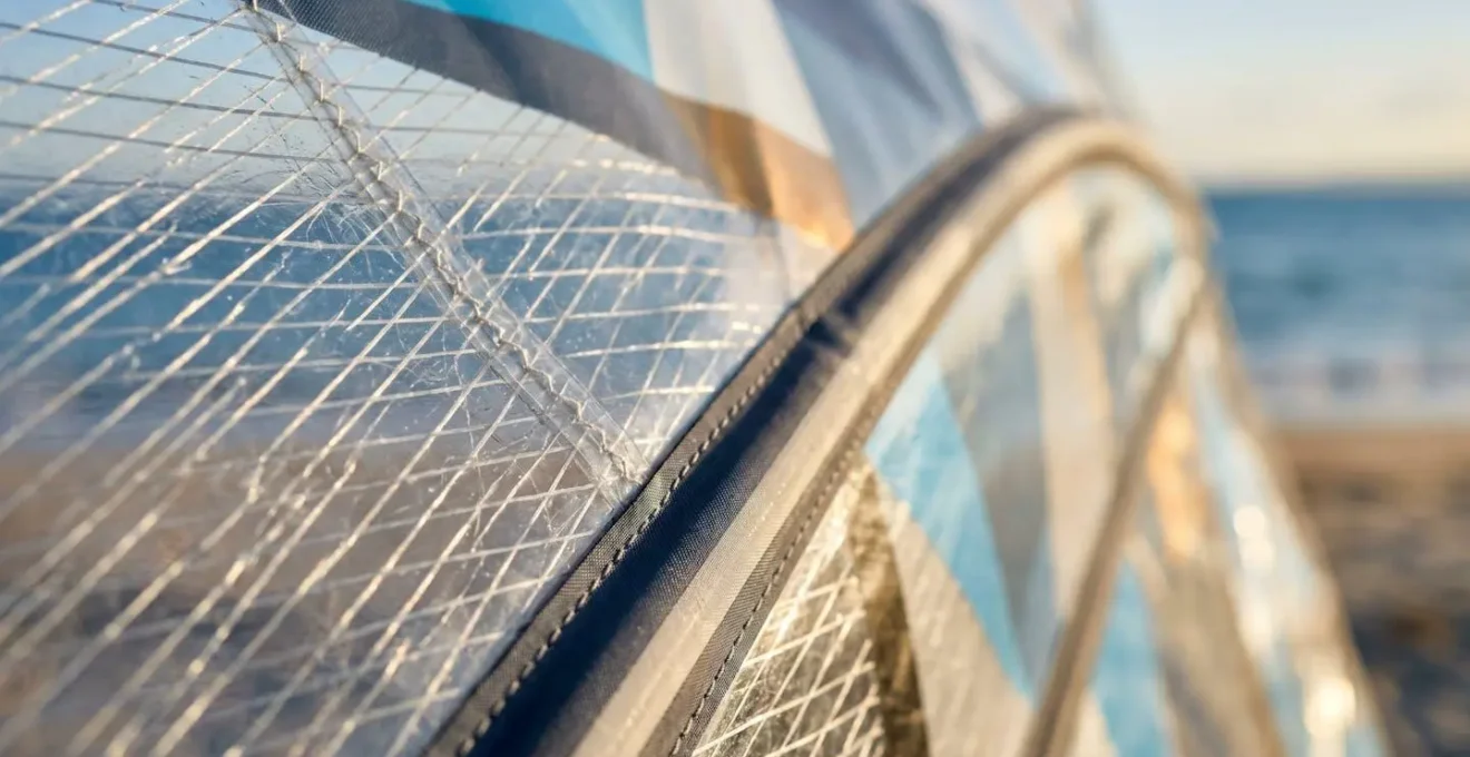 Gros plan sur une voile de windsurf moderne en monofilm avec lattes rigides, détails techniques et textures visibles